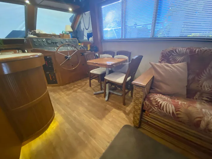 The Jolly Rogers Yacht Photos Pics 1987 Hi-Star Sportfish boat interior with wooden flooring, dining table, and steering wheel.