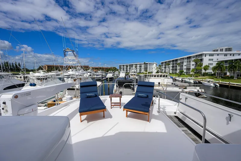 Sapphire Yacht Photos Pics 2009 Hatteras Enclosed Bridge yacht with sun loungers, docked in a marina under blue skies.