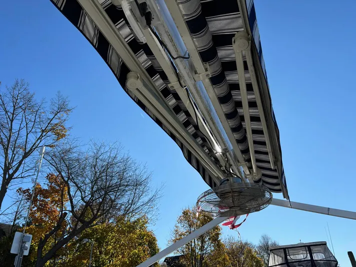  Yacht Photos Pics Custom MKI Pontoon Boat 2022 with striped canopy, under clear blue sky.