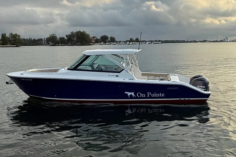 On Pointe Yacht Photos Pics 2016 Pursuit DC 325 Dual Console boat on calm water at sunset.