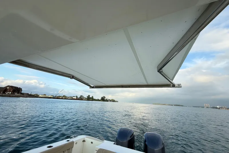 On Pointe Yacht Photos Pics 2016 Pursuit DC 325 Dual Console boat with canopy, overlooking serene waters and distant shoreline.