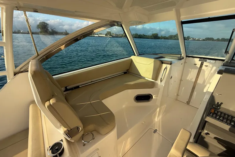 On Pointe Yacht Photos Pics 2016 Pursuit DC 325 Dual Console interior with beige seating, overlooking calm waters.