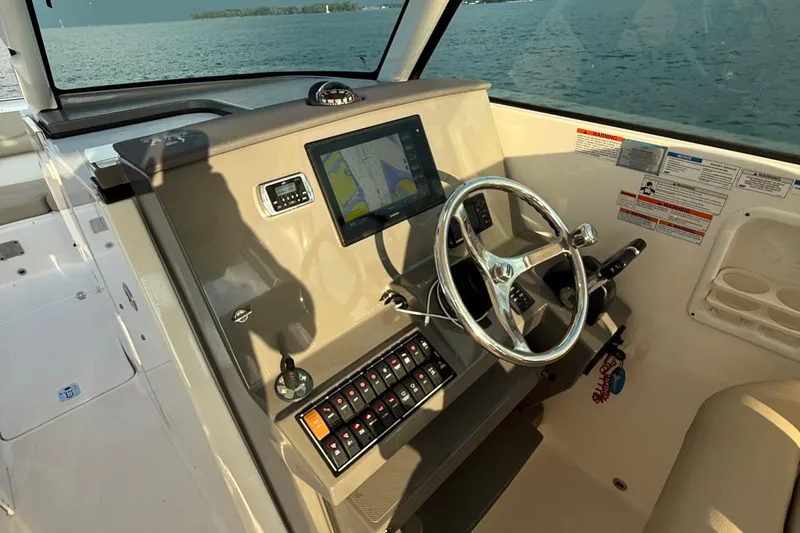 On Pointe Yacht Photos Pics 2016 Pursuit DC 325 Dual Console boat dashboard with steering wheel and navigation display.