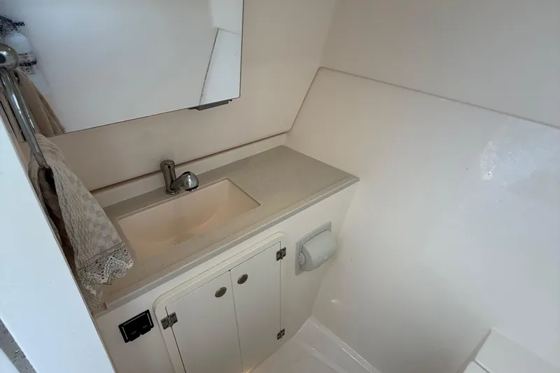 On Pointe Yacht Photos Pics 2016 Pursuit DC 325 Dual Console boat bathroom with sink, mirror, and storage cabinet.