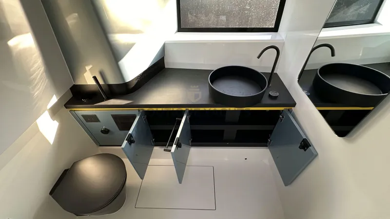 Hull #5 Yacht Photos Pics Modern bathroom interior in 2024 Maori 46ft yacht with sleek black fixtures and open cabinets.