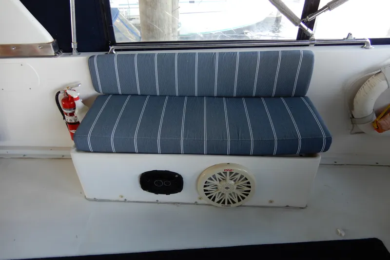 Yacht Photos Pics Blue-striped bench seat on 1989 Jefferson 46 Sundeck boat, featuring a speaker and fire extinguisher.