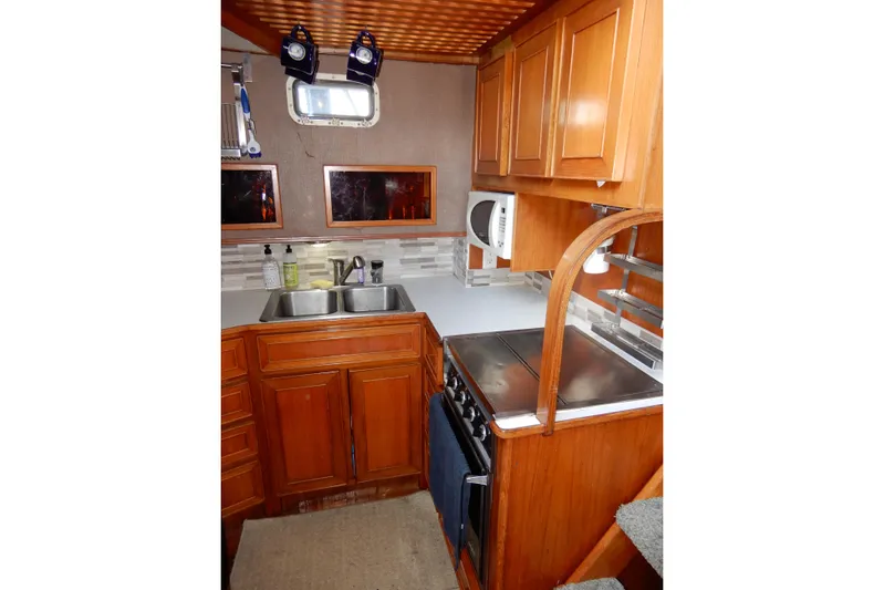  Yacht Photos Pics 1989 Jefferson 46 Sundeck yacht kitchen with wooden cabinets, stove, and double sink.