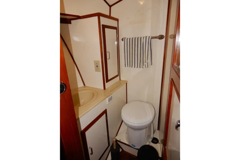  Yacht Photos Pics 1989 Jefferson 46 Sundeck bathroom with sink, toilet, and striped towel.