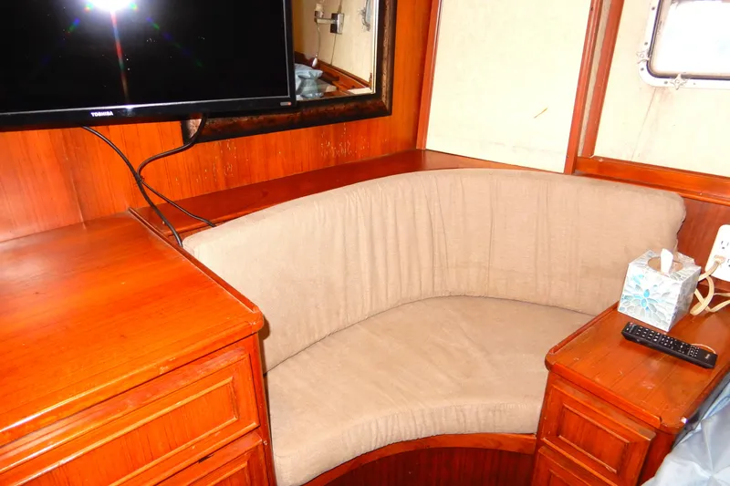  Yacht Photos Pics 1989 Jefferson 46 Sundeck interior with curved seating, TV, and wooden cabinetry.