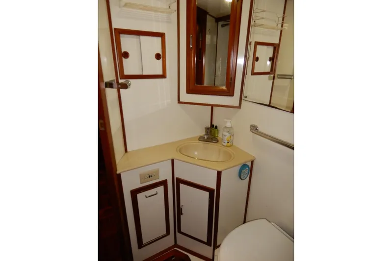  Yacht Photos Pics 1989 Jefferson 46 Sundeck yacht bathroom with sink, mirror, and storage cabinets.