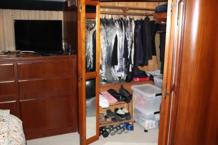 Eternity Yacht Photos Pics 1985 Hatteras 58 Motor Yacht interior closet with clothes, shoes, and storage boxes.