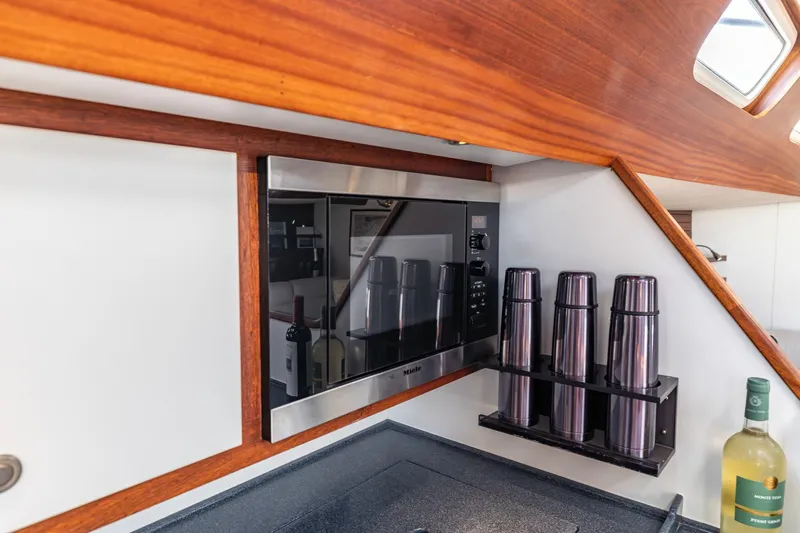 Red Rooster Yacht Photos Pics Interior of 2008 Van De Stadt Stadtship 70 yacht kitchen with microwave and wine bottles.