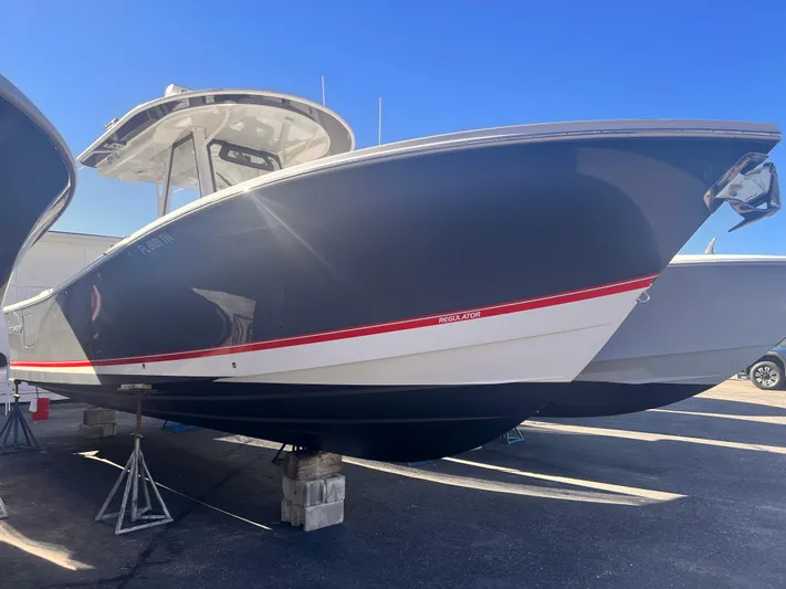  Yacht Photos Pics 2020 Regulator 31 boat with sleek design, dark hull, and red accent stripe.