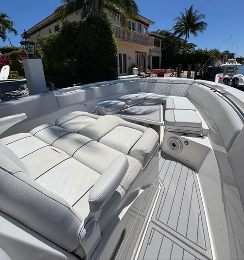 Seakeeper And Joystick Yacht Photos Pics 2020 Sea Fox 368 Commander boat with luxurious seating, docked near a waterfront home.