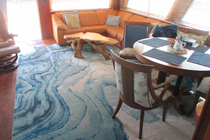 Hattitude Yacht Photos Pics Interior of 1981 Hatteras 61 Motor Yacht with blue abstract rug and wooden furniture.