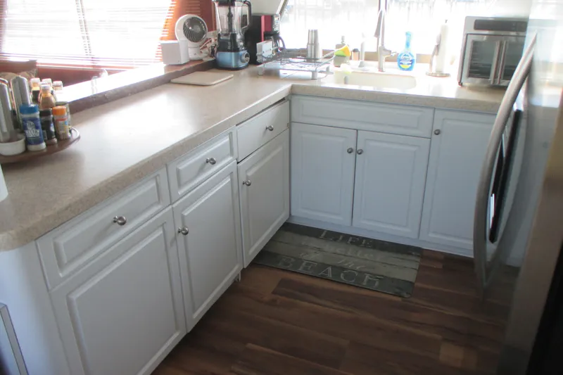 Hattitude Yacht Photos Pics Kitchen interior of 1981 Hatteras 61 Motor Yacht with white cabinets and wooden floor.