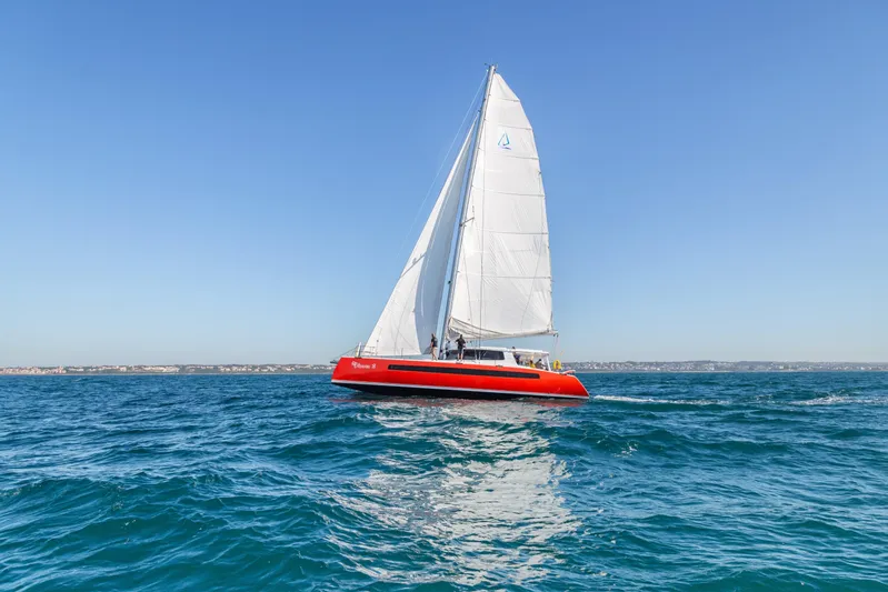 Ohana 8 Yacht Photos Pics Red Balance 526 sailboat from 2020 gliding on open sea under clear blue sky.