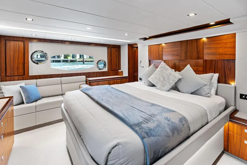 Seas The Moment Yacht Photos Pics Luxurious 2022 Riviera 6000 Sport Yacht bedroom with elegant wood paneling and plush bedding.