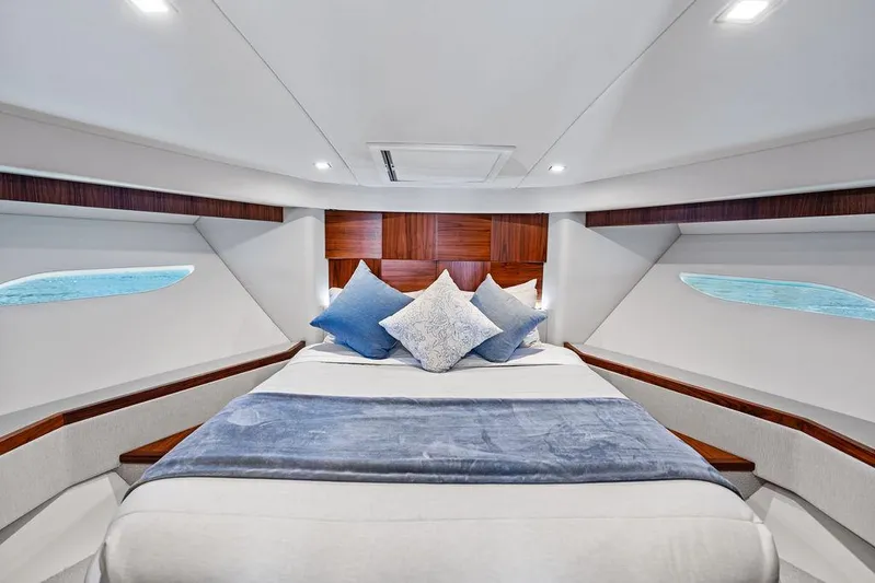 Seas The Moment Yacht Photos Pics Luxurious bedroom interior of 2022 Riviera 6000 Sport Yacht with elegant bedding and modern design.