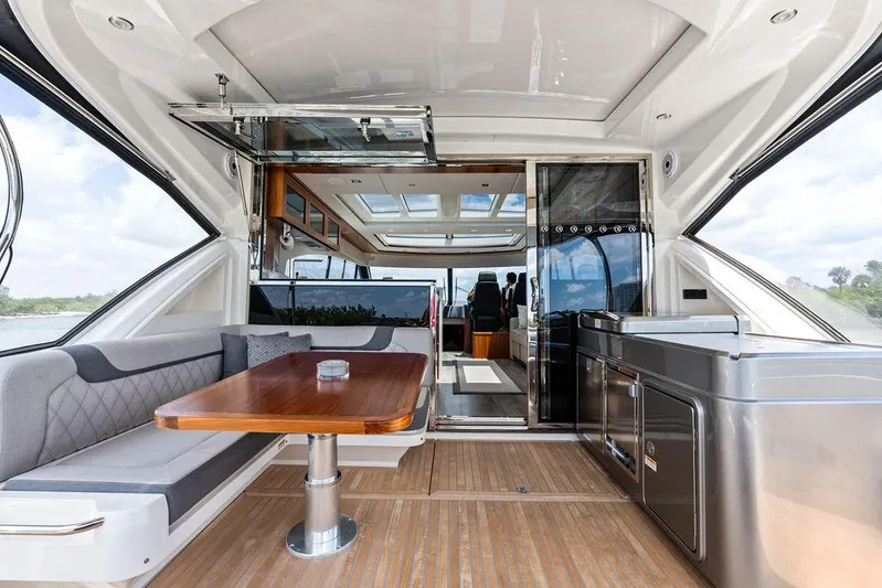 Seas The Moment Yacht Photos Pics 2022 Riviera 6000 Sport Yacht interior with modern seating and kitchen area.
