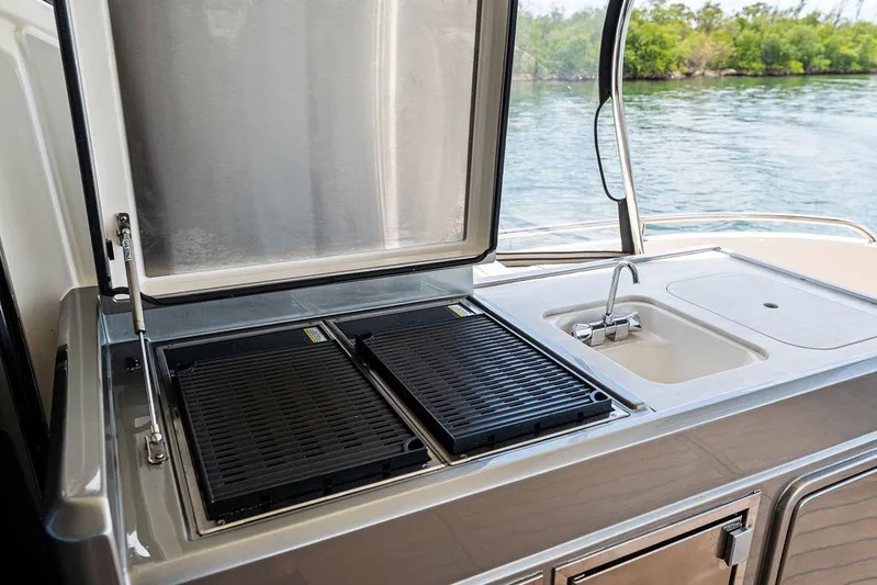 Seas The Moment Yacht Photos Pics Outdoor kitchen on 2022 Riviera 6000 Sport Yacht with grill and sink by the water.
