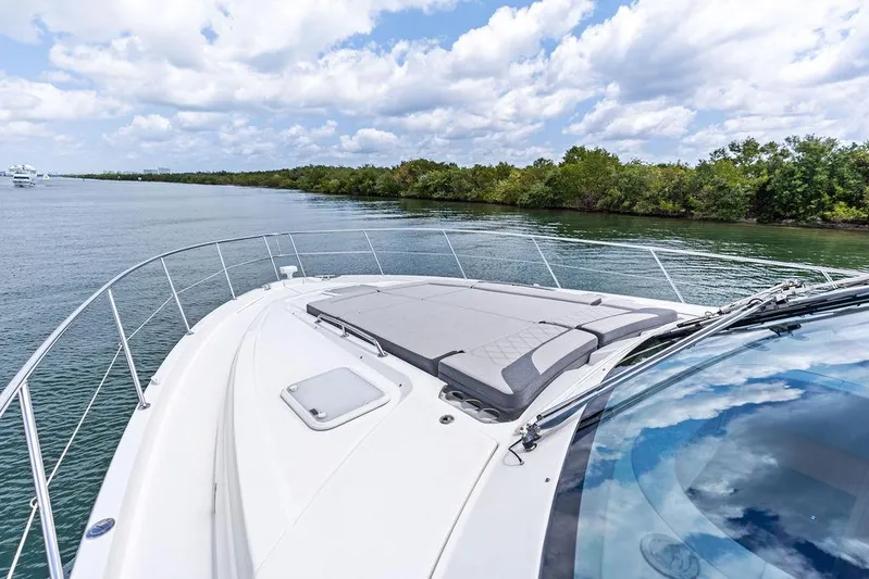 Seas The Moment Yacht Photos Pics 2022 Riviera 6000 Sport Yacht cruising on a serene waterway under a partly cloudy sky.