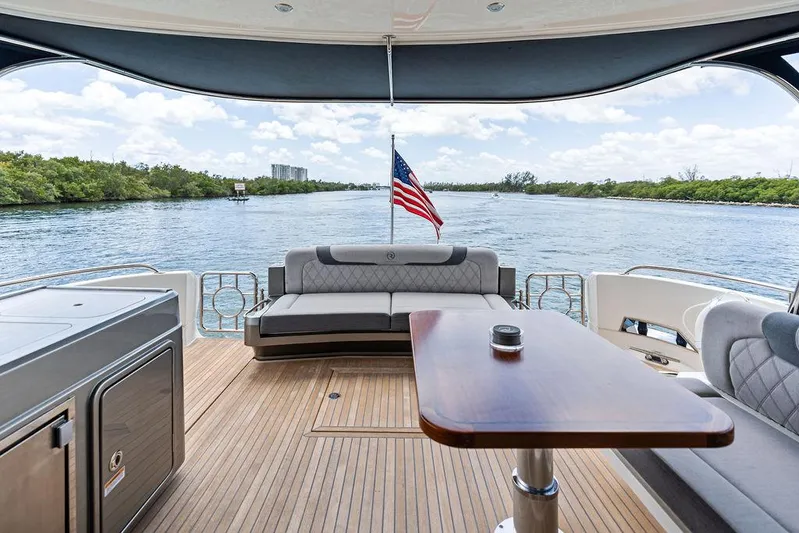 Seas The Moment Yacht Photos Pics 2022 Riviera 6000 Sport Yacht deck with seating, table, and scenic water view.