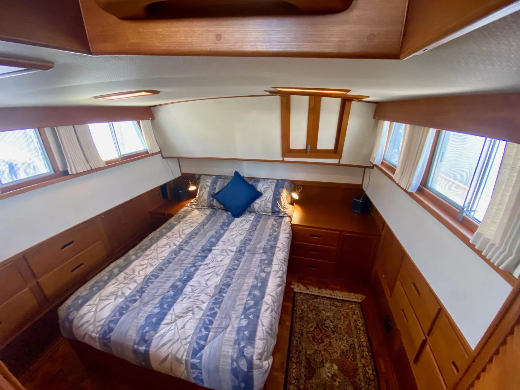 Cozy bedroom in 1997 Grand Banks Classic yacht with wood accents and natural light.
