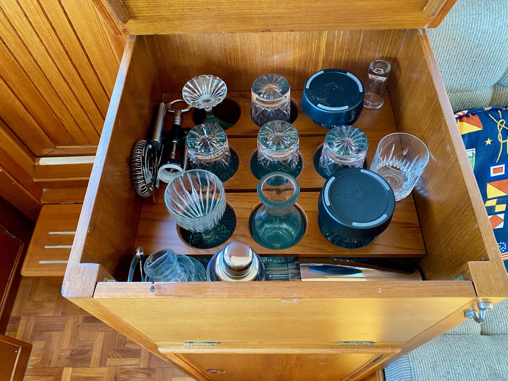Barware collection in a wooden cabinet on a 1997 Grand Banks Classic boat.