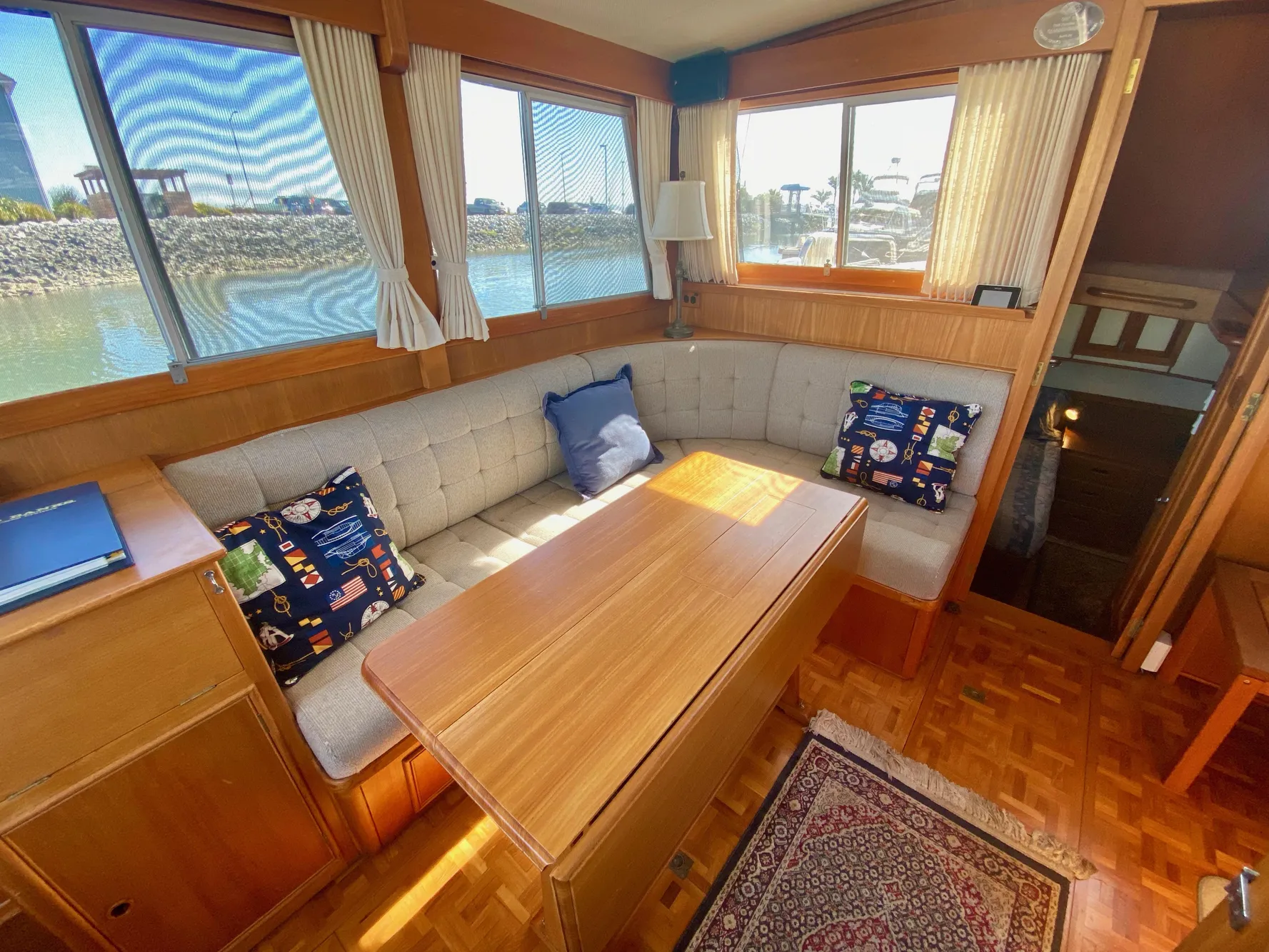Cozy 1997 Grand Banks Classic yacht interior with cushioned seating and wooden table.