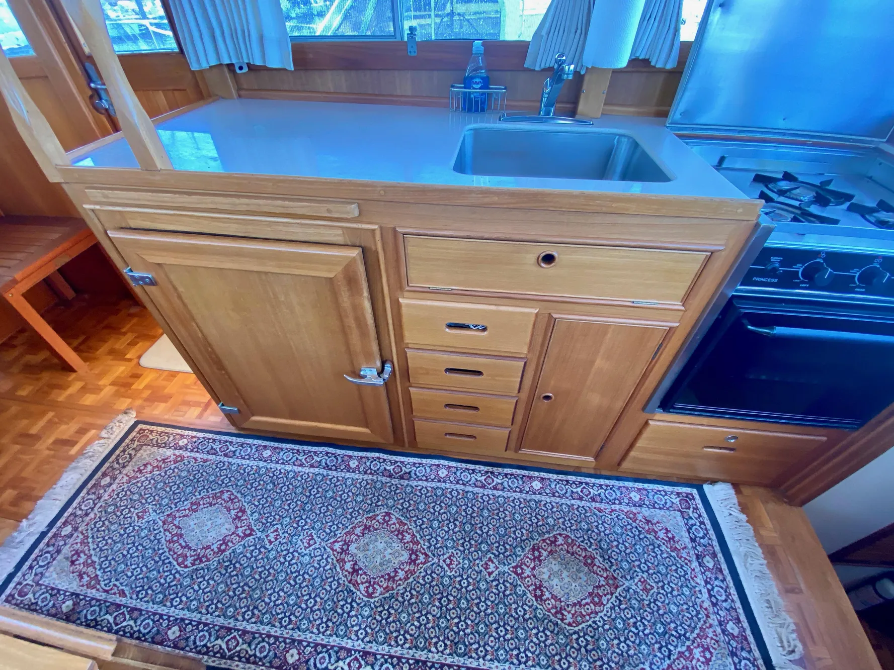 1997 Grand Banks Classic yacht kitchen with wooden cabinets, stove, and patterned rug.
