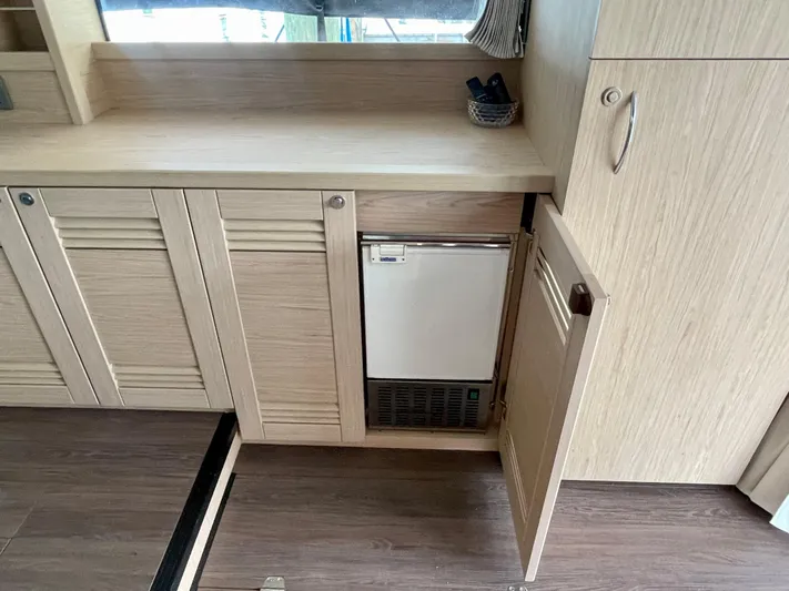  Yacht Photos Pics 2026 Beneteau Swift Trawler 41 interior with wooden cabinetry and built-in mini fridge.