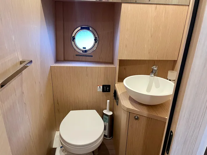  Yacht Photos Pics 2026 Beneteau Swift Trawler 41 bathroom with porthole, toilet, and modern sink.