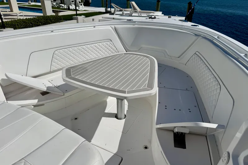  Yacht Photos Pics 2024 Intrepid 407 Nomad FE boat interior with white seating and table, docked by the water.