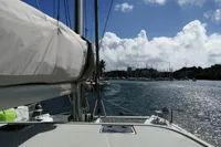 Nautitech 40 Open 2018 catamaran sailing towards marina under a partly cloudy sky.