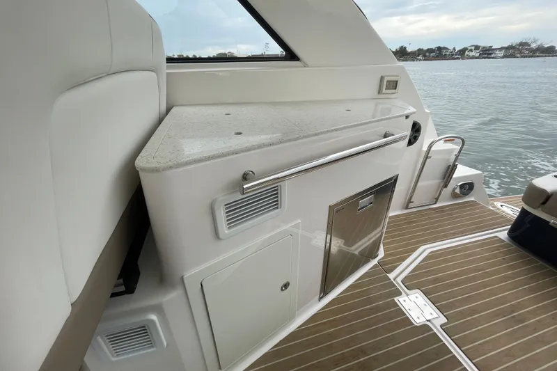 Motivated Yacht Photos Pics 2017 Regal 35 Sport Coupe interior with sleek countertop and wooden deck by the water.