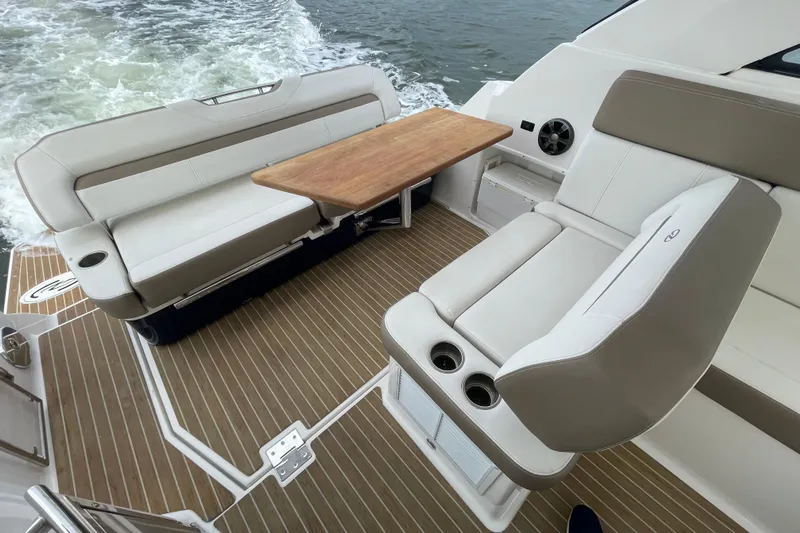 Motivated Yacht Photos Pics 2017 Regal 35 Sport Coupe interior with beige seating and wooden table on deck.
