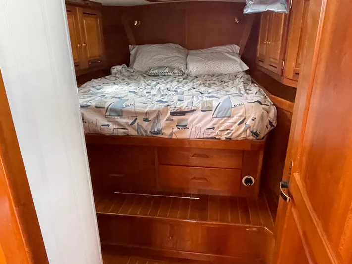 Full Sail Yacht Photos Pics Cozy cabin interior of 2003 Tartan 4600 sailboat with wooden furnishings and nautical-themed bedding.