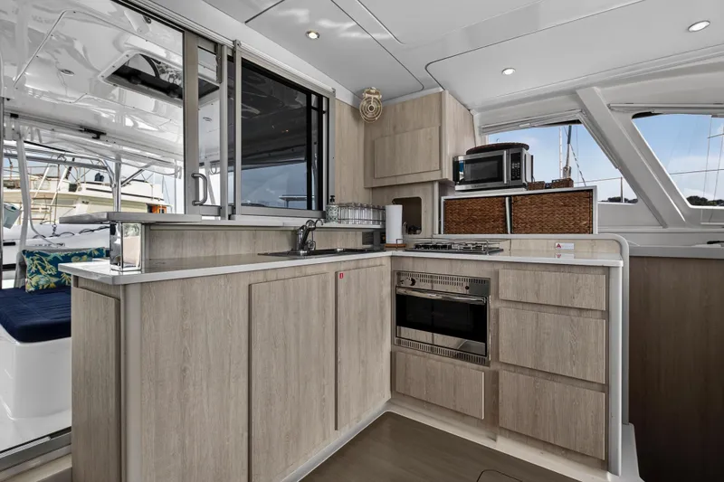  Yacht Photos Pics Modern kitchen interior of 2016 Leopard 44 Owners Version catamaran with wood cabinetry and appliances.
