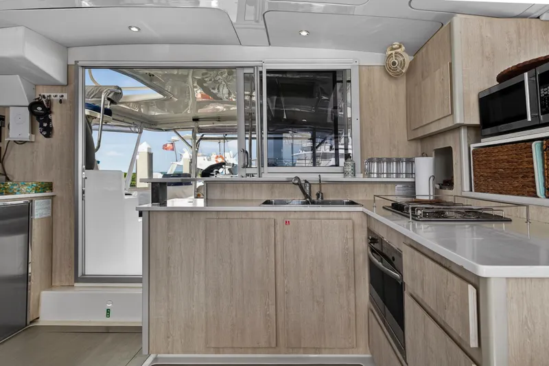  Yacht Photos Pics Modern kitchen interior of 2016 Leopard 44 Owners Version catamaran, featuring sleek appliances and wood cabinetry.