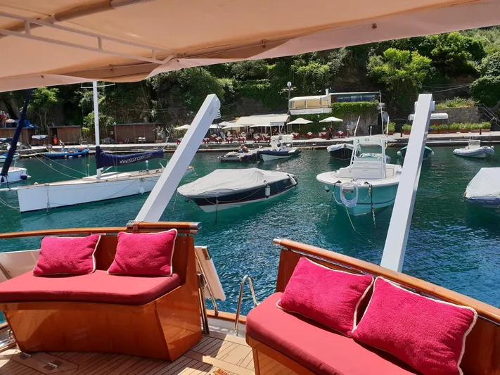  Yacht Photos Pics Luxury yacht deck with red cushions, overlooking a serene marina with boats. Feadship CARAVELLE 23, 1965.
