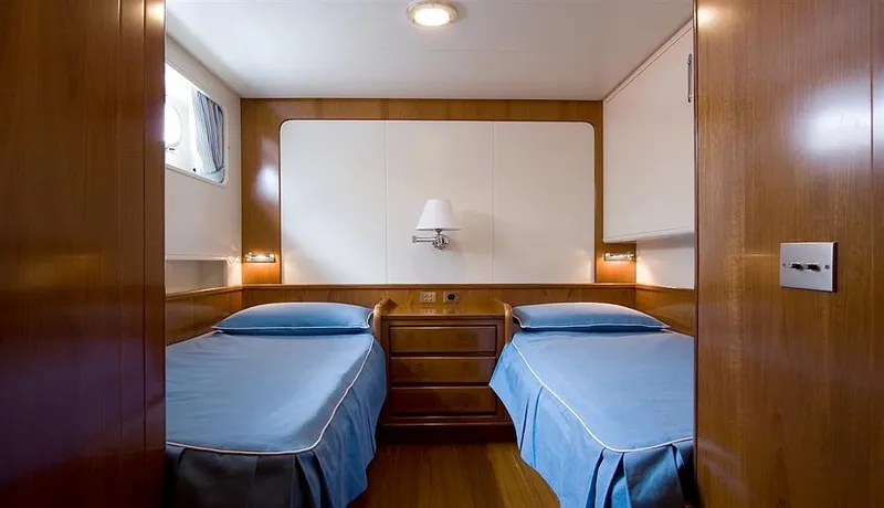  Yacht Photos Pics Twin cabin interior of 1965 Feadship CARAVELLE 23 yacht with wooden paneling and blue bedding.