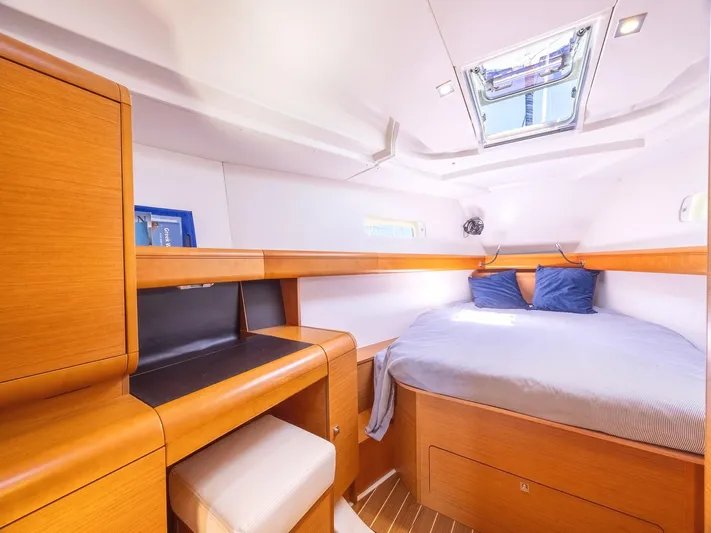  Yacht Photos Pics Interior cabin of 2013 Jeanneau Sun Odyssey 439, featuring cozy bed and wooden furnishings.