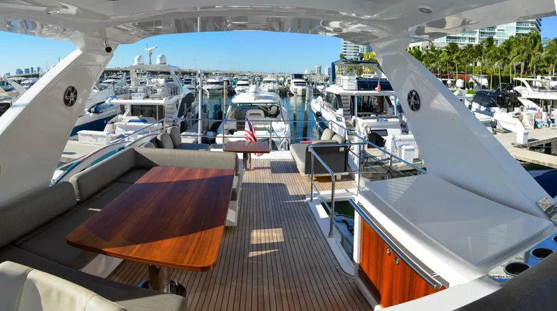 Cerulean Yacht Photos Pics 2018 Azimut 66 yacht docked at a marina, featuring a spacious deck with seating and a wooden table.