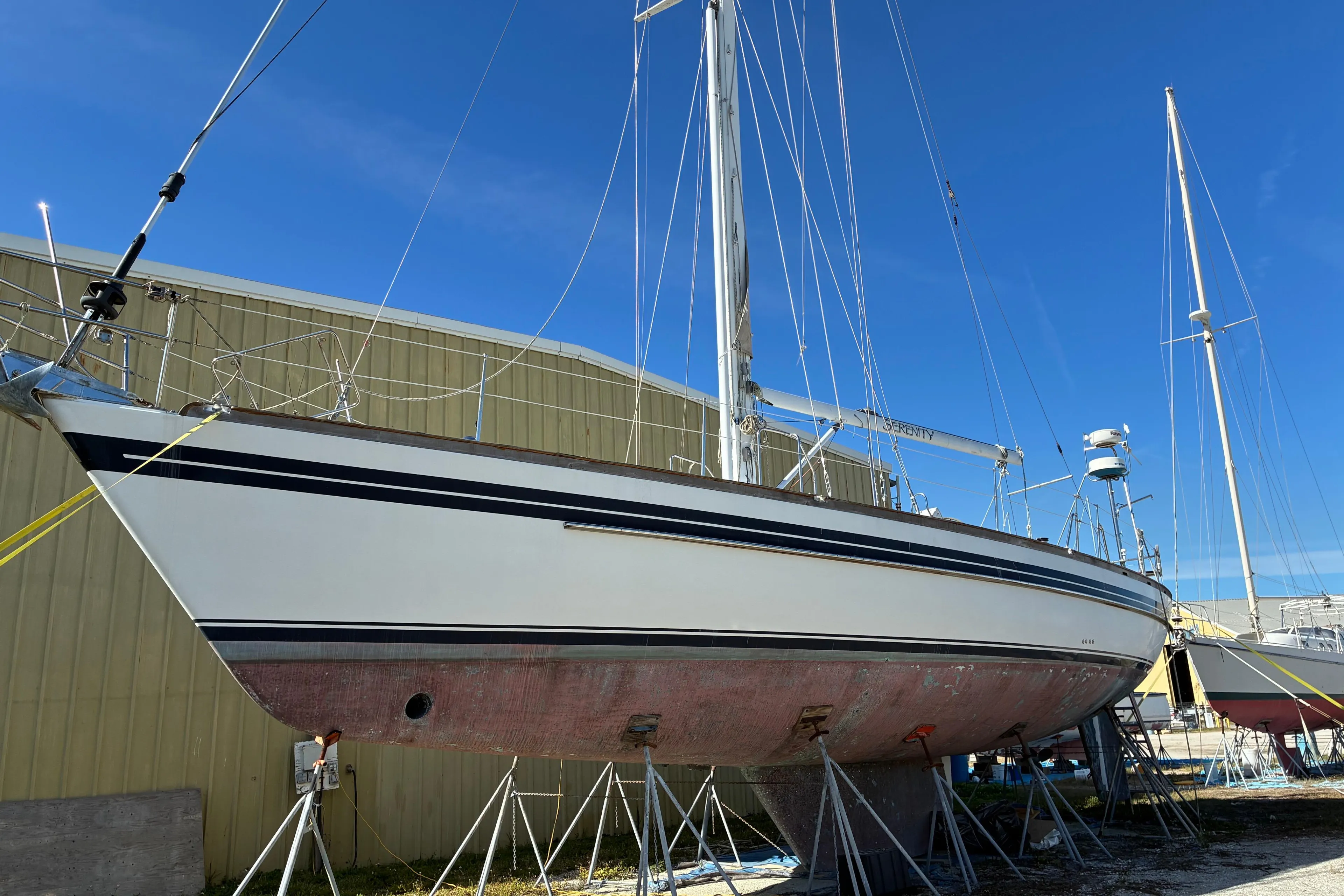 1998 Tayana 55 sailboat on stands, ready for maintenance, against a clear blue sky.
