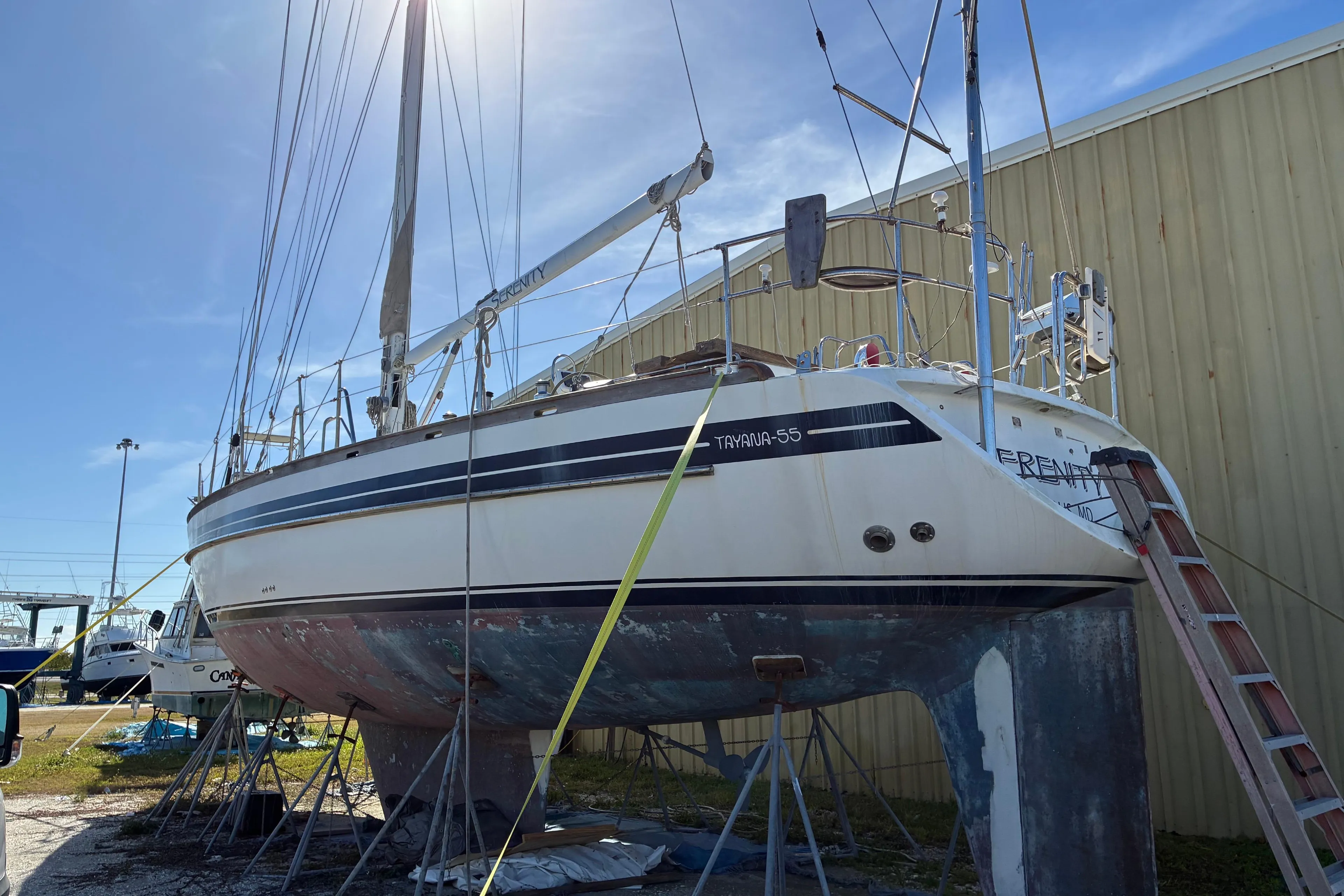 1998 Tayana 55 sailboat on dry dock, undergoing maintenance under clear blue sky.