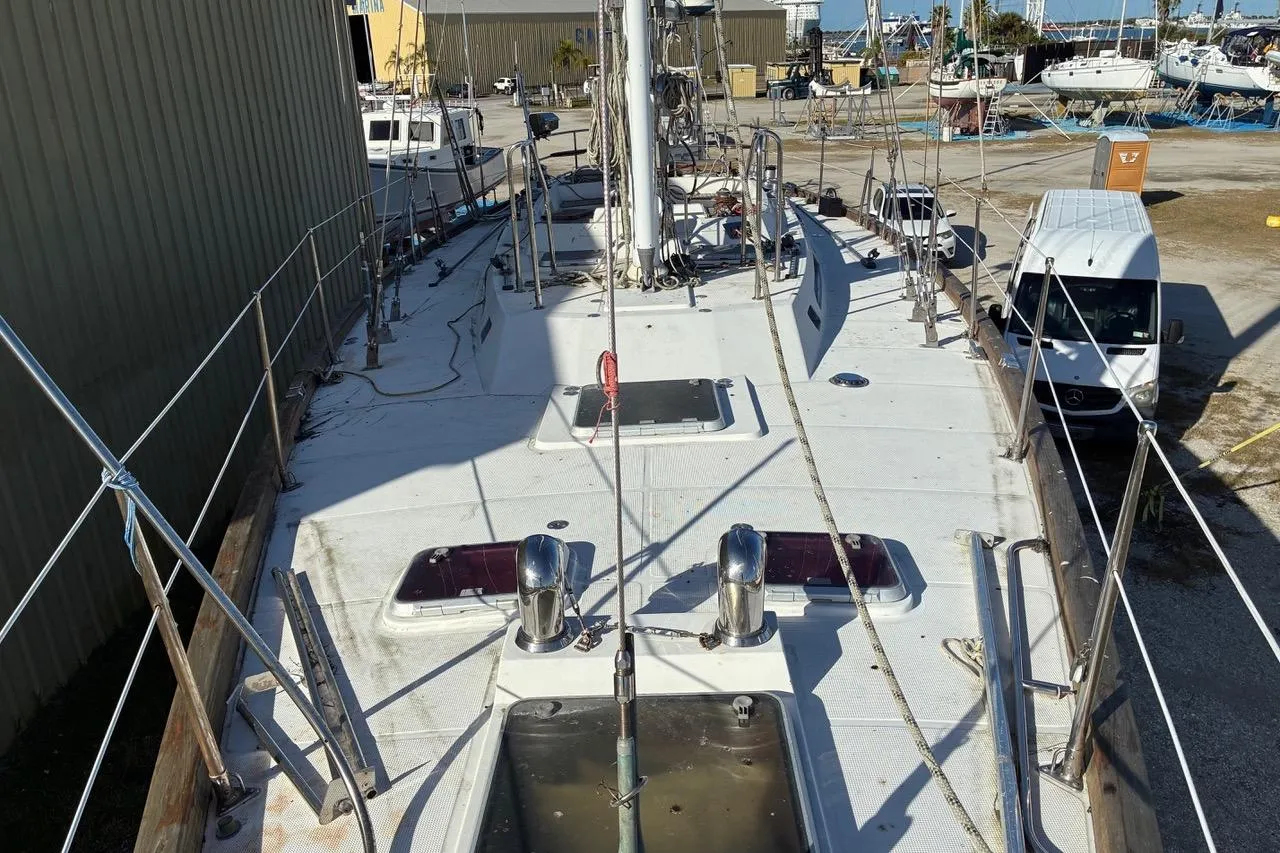 1998 Tayana 55 sailboat on land, viewed from deck, surrounded by other boats.