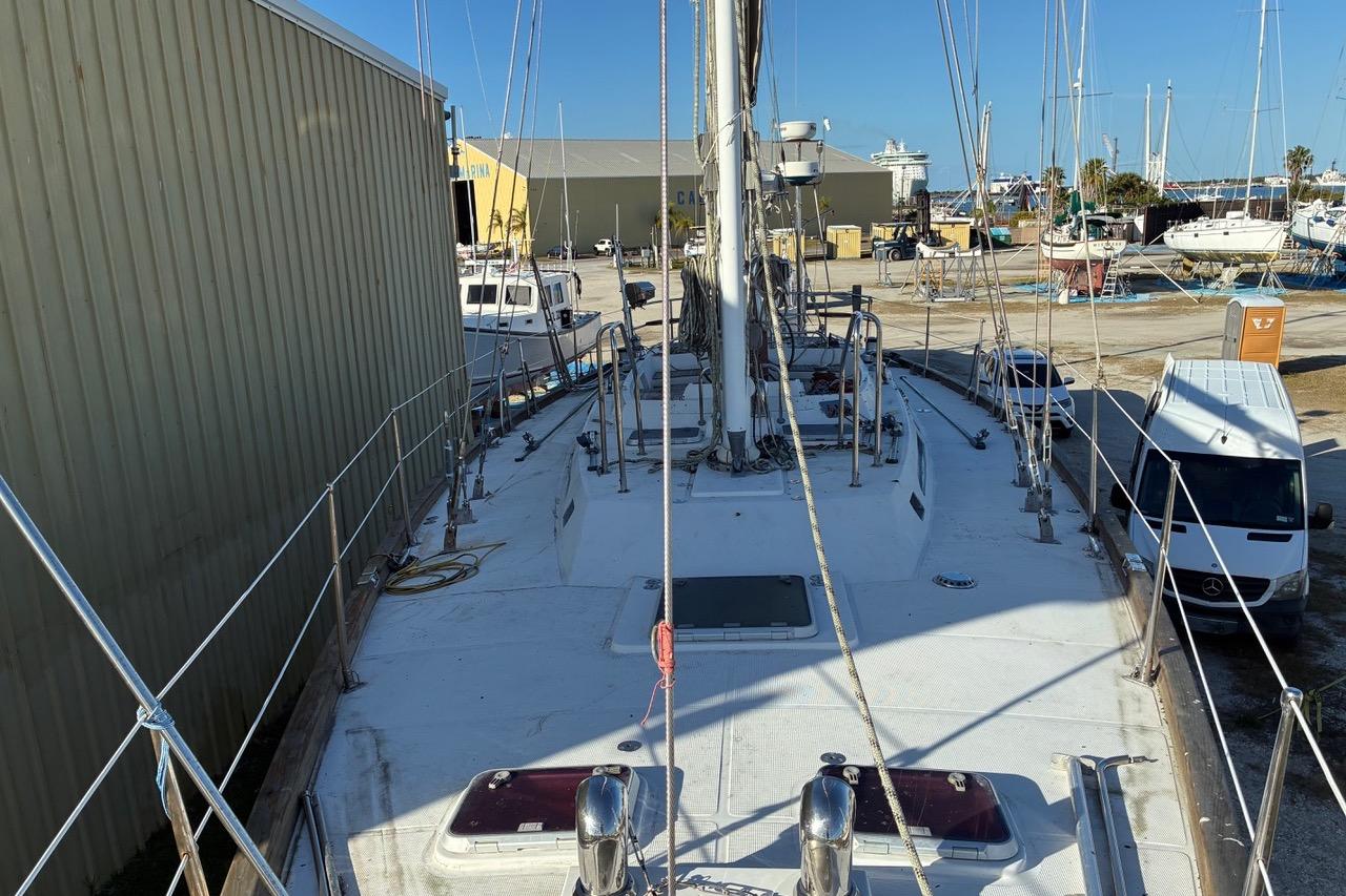 Sailboat Tayana 55, 1998 model, docked in a marina with surrounding boats and vehicles.