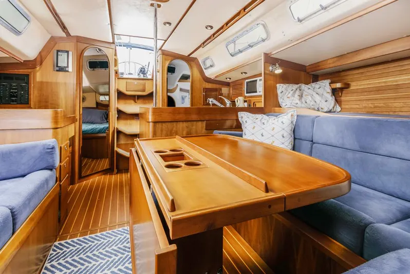 Lark Yacht Photos Pics Luxurious interior of a 2001 J Boats 46 sailboat with wooden finishes and blue seating.