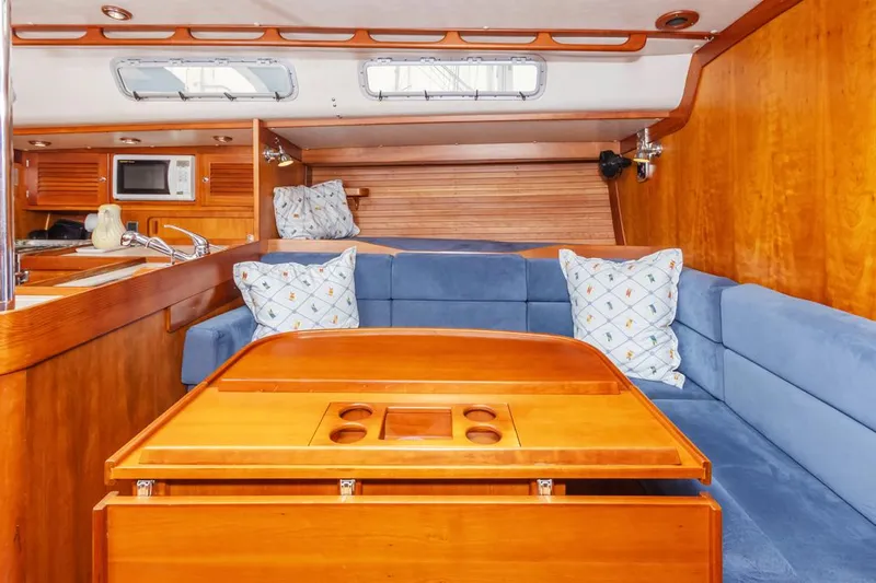 Lark Yacht Photos Pics Interior of 2001 J Boats 46 sailboat with wooden table, blue seating, and pillows.